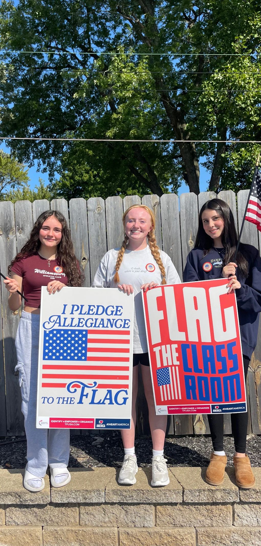 Female students holding “Flag the Classroom” posters.