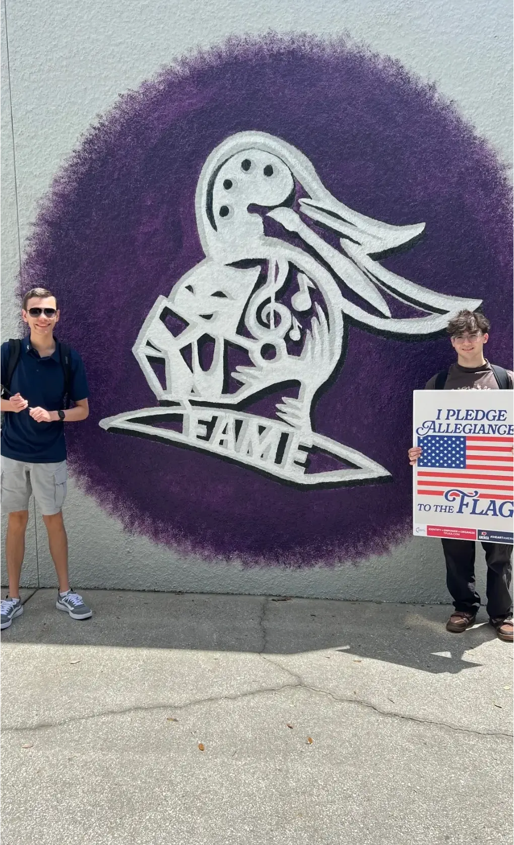 Boys holding a poster, with graffiti reading “Fame” in the background.